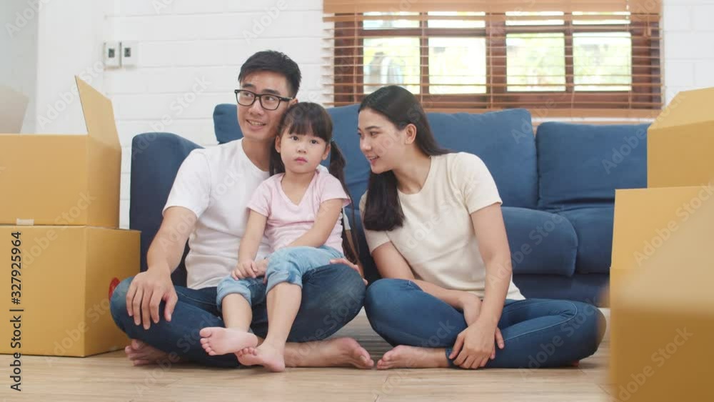 Happy Asian young family homeowners bought new house. Korean Mom, Dad, and daughter embracing looking forward to future in new home after moving in relocation sitting on floor with boxes together. Happy Asian young family homeowners bought new house. Korean Mom, Dad, and daughter embracing looking forward to future in new home after moving in relocation sitting on floor with boxes together.