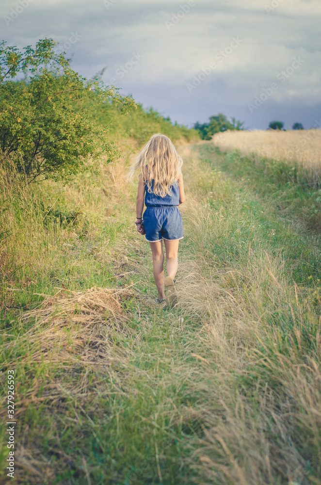 little child walking in green grass in beautiful scenic countryside