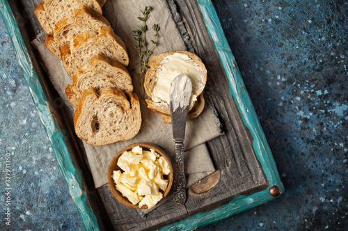 Slices of bread with butter in wooden bowl and vintage knife