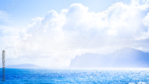 Sandy beach with mountains on background. Mountains are covered with grass  and has sheer cliffs from sea. Sky is cloudy