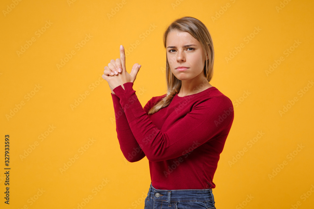 Confident young blonde woman girl in casual clothes posing isolated on yellow orange background studio portrait. People sincere emotions lifestyle concept. Mock up copy space. Holding hands like gun. Confident young blonde woman girl in casual clothes posing isolated on yellow orange background studio portrait. People sincere emotions lifestyle concept. Mock up copy space. Holding hands like gun.