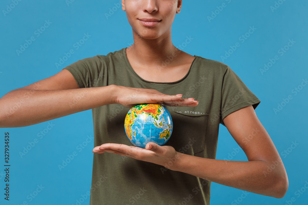 Cropped image of young african american woman girl in casual t-shirt posing isolated on blue background studio portrait. People emotions lifestyle concept. Mock up copy space. Hold Earth world globe. Cropped image of young african american woman girl in casual t-shirt posing isolated on blue background studio portrait. People emotions lifestyle concept. Mock up copy space. Hold Earth world globe.