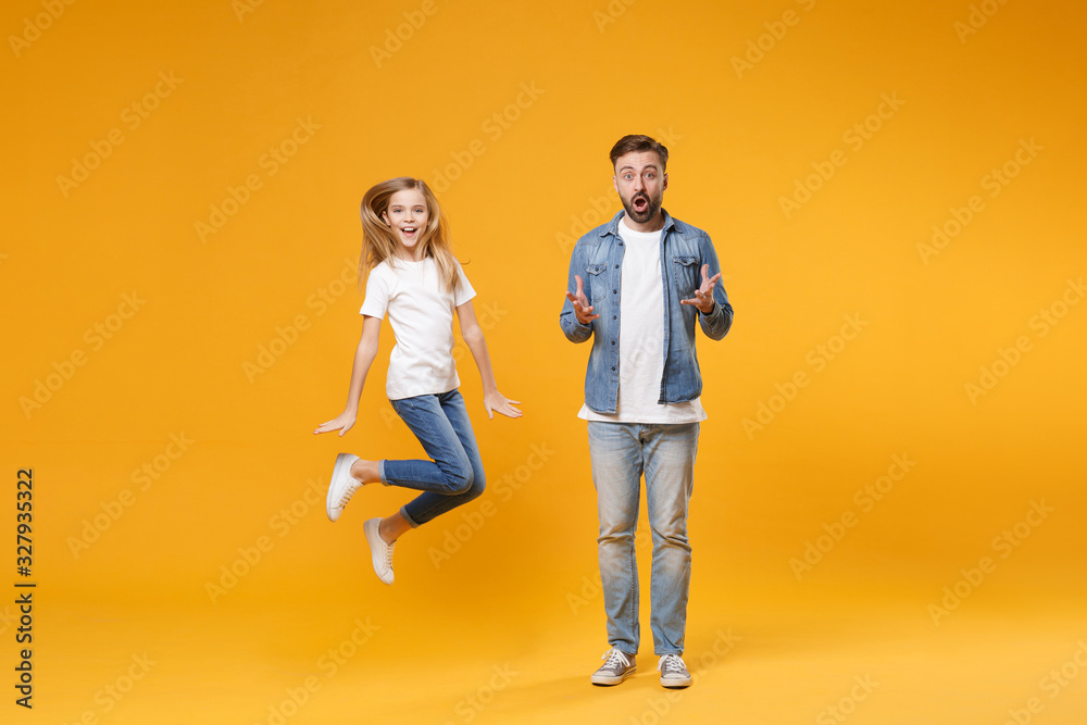 Fototapeta premium Excited amazed bearded man in casual clothes have fun with child baby girl. Father little kid daughter isolated on yellow background. Love family parenthood childhood concept. Spreading hands jumping.