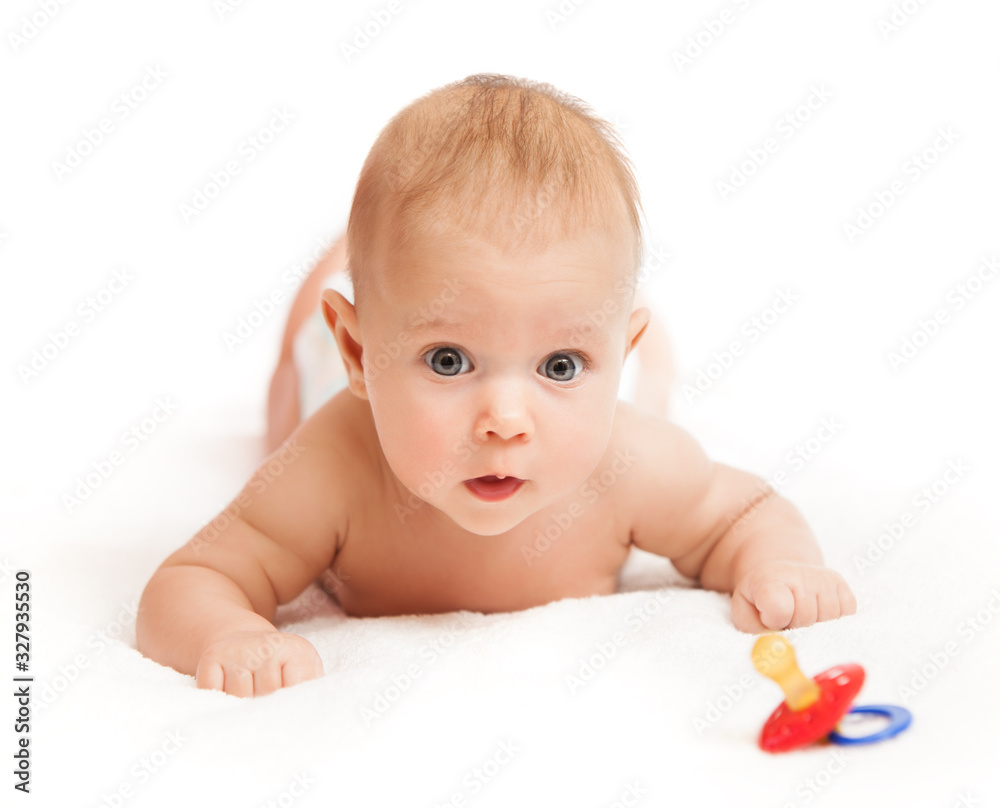 Close-up portrait of a curious little pretty girl lying on a divan and playing with a rattle on a white background. The concept of development of babies and care. Copyspace Close-up portrait of a curious little pretty girl lying on a divan and playing with a rattle on a white background. The concept of development of babies and care. Copyspace