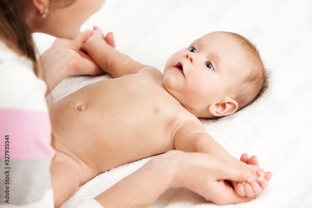 Close up of adorable infant lying on soft white sheets and looking at mommy. Young woman holding tiny hands of cute newborn child. Concept of motherhood and infancy. Close up of adorable infant lying on soft white sheets and looking at mommy. Young woman holding tiny hands of cute newborn child. Concept of motherhood and infancy.
