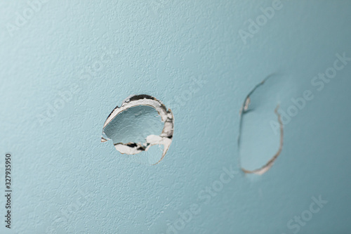 Photography turquoise blue wall in a home with two holes in the sheetrock from a wall being
