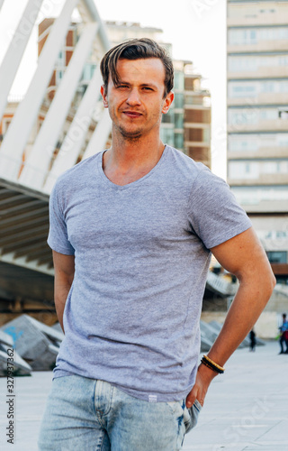 Young Caucasian Man in Silver t-shirt with Bridge Background