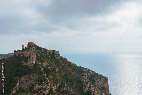 The panoramic view of a medieval fortified castle of an old French village named   ze on top of a cliff and the Mediterranean sea