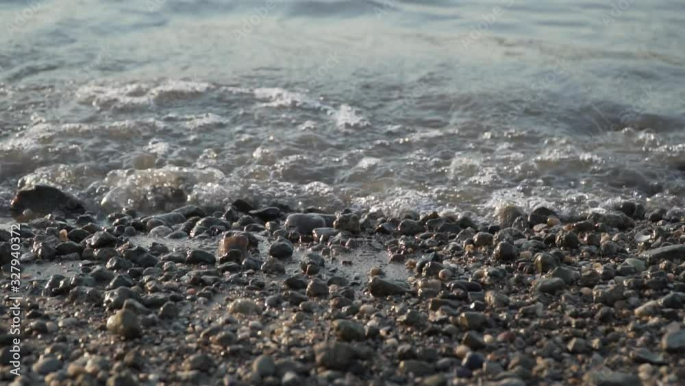 Waves are splashing pebbles on a river shore
