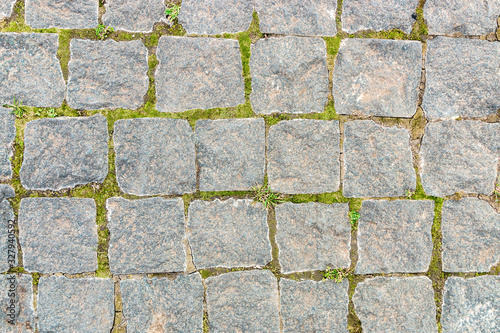 grey stone background from old square paver bricks and green grass between them for designs