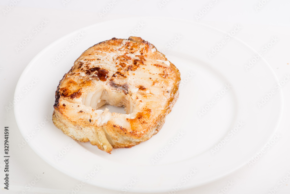 grilled fish steak on a white plate with a place for garnish grilled fish steak on a white plate with a place for garnish
