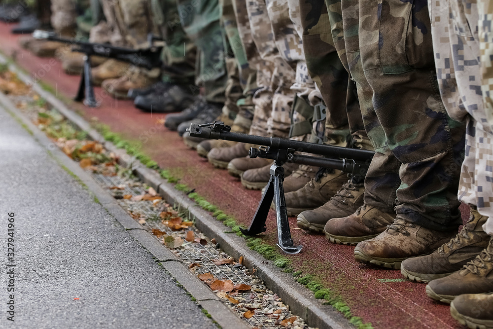 Fototapeta premium Section of soldiers legs in military uniform and boots standing in line at camp