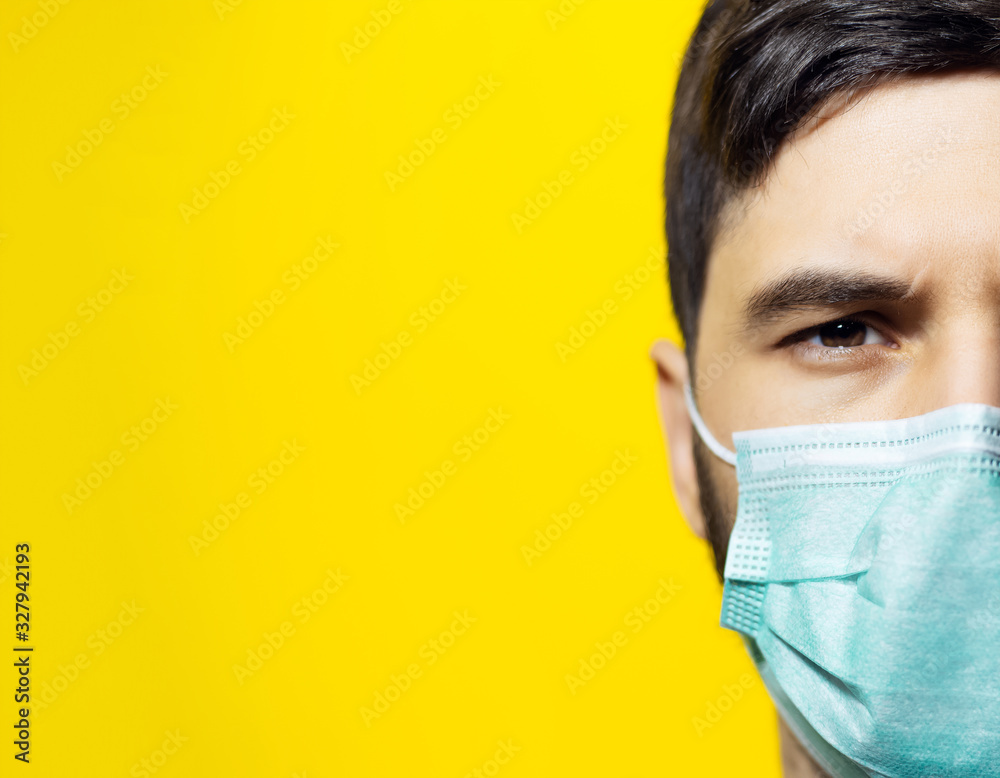 Close-up portrait of male face, wearing medical flu mask on background of yellow color with copy space. Close-up portrait of male face, wearing medical flu mask on background of yellow color with copy space.