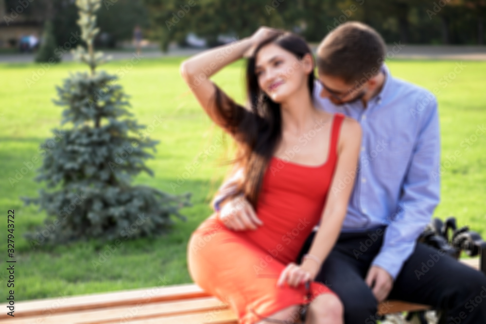 Beautiful couple of man and woman sitting on a bench in a park. Romantic theme with a girl and a guy. Spring Summer theme  relationship, love, Valentine's day