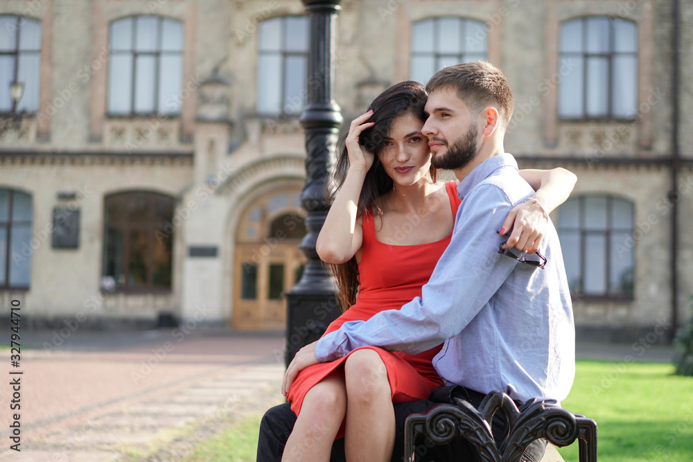 Beautiful couple of man and woman sitting on a bench in a park. Romantic theme with a girl and a guy. Spring Summer theme  relationship, love, Valentine's day