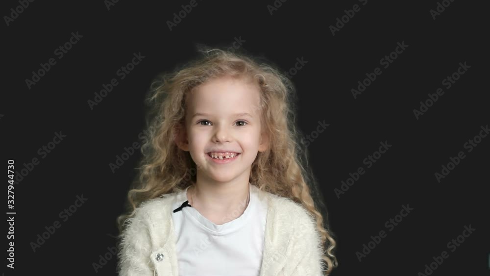 Little girl with blond curly hair, white shirt and white knitted jacket