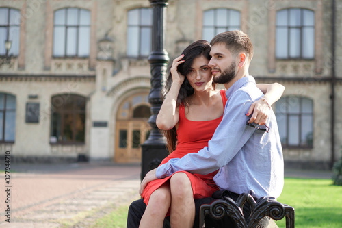 Beautiful couple of man and woman sitting on a bench in a park. Romantic theme with a girl and a guy. Spring Summer theme relationship, love, Valentine's day