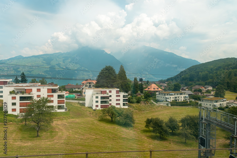 view from the train window. A train passes by residential buildings, in a distant mountain in clouds and haze.