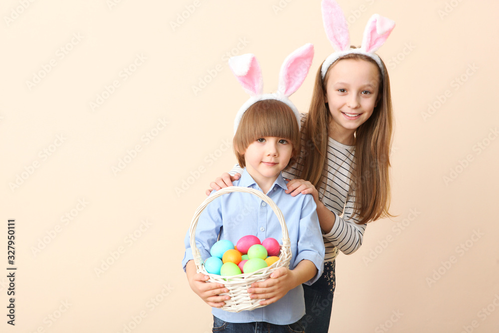 Cute little boy and girl in rabbit ears and with an Easter basket on a colored background. Easter background with place to insert text. Family Easter traditions.