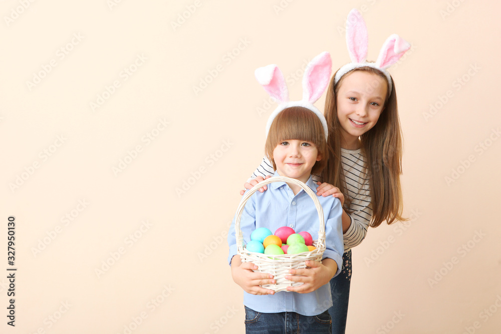 Cute little boy and girl in rabbit ears and with an Easter basket on a colored background. Easter background with place to insert text. Family Easter traditions. Cute little boy and girl in rabbit ears and with an Easter basket on a colored background. Easter background with place to insert text. Family Easter traditions.