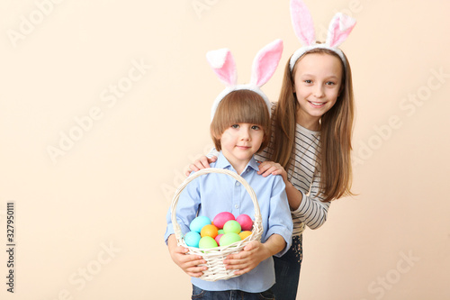 Cute little boy and girl in rabbit ears and with an Easter basket on a colored background. Easter background with place to insert text. Family Easter traditions.
