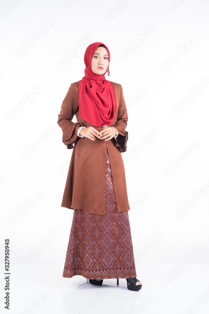 Full length portrait of a beautiful female model wearing a modern kebaya dress and hijab, a lifestyle apparel for Muslim women isolated on white background. Beauty and hijab fashion concept.