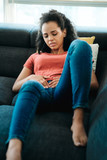Young Black Woman With Menstrual Pain Lying On Sofa