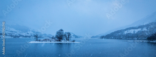 snow falling over loch leven and eilean nam ban, an island in the loch, in the argyll region of the highlands of scotland during winter near glencoe and fort william