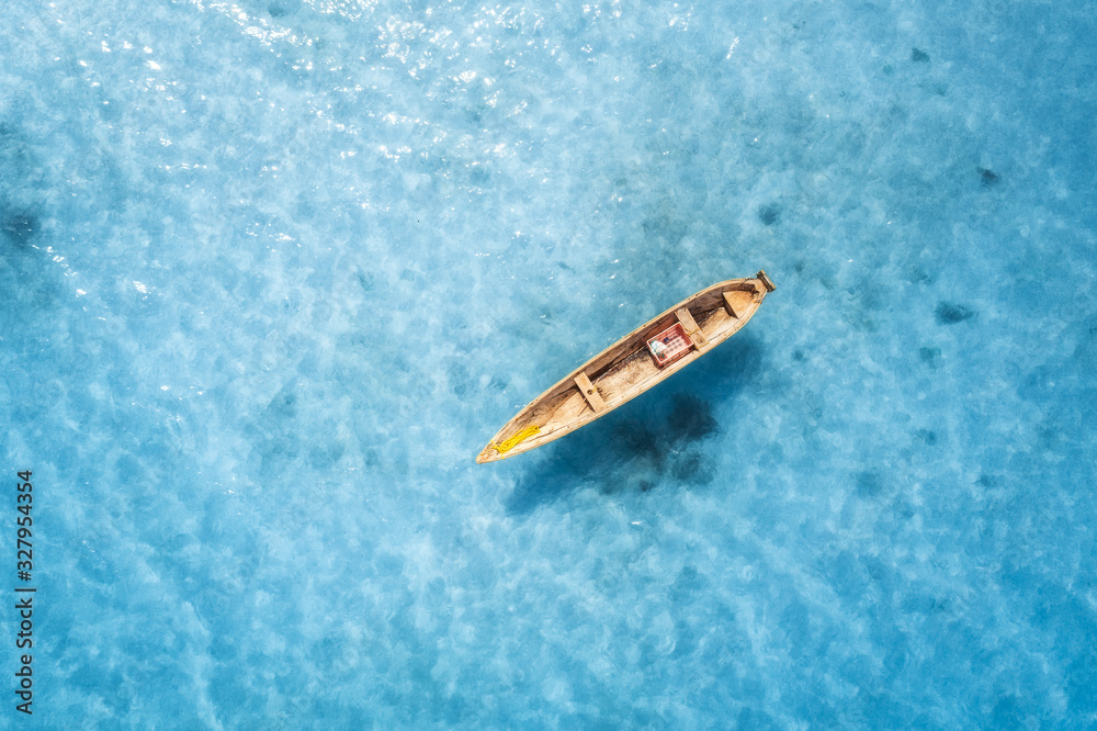 Aerial view of the fishing boat in transparent blue water at sunny day in summer. Top view from above of boat, sandy beach. Indian ocean in Zanzibar, Africa. Landscape with canoe and clear sea. Travel Aerial view of the fishing boat in transparent blue water at sunny day in summer. Top view from above of boat, sandy beach. Indian ocean in Zanzibar, Africa. Landscape with canoe and clear sea. Travel