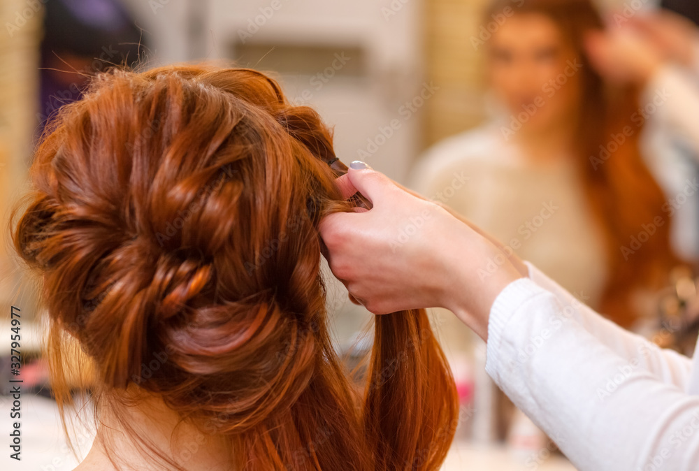 Beautiful girl with long redhair, hairdresser weaves a braid, close-up in a beauty salon. Professional hair care and creating hairstyles. Beautiful girl with long redhair, hairdresser weaves a braid, close-up in a beauty salon. Professional hair care and creating hairstyles.