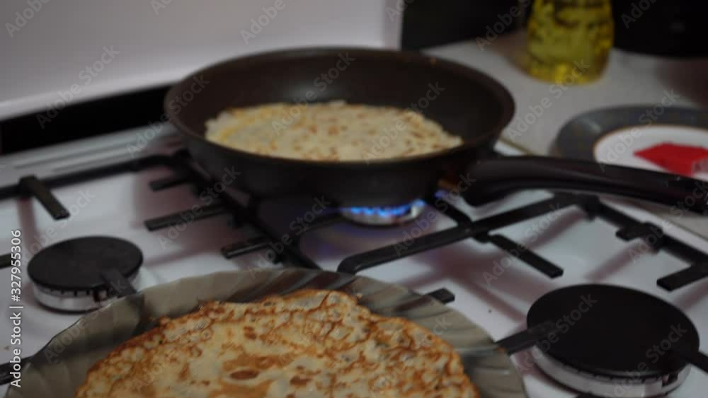 Europe, Kiev, Ukraine - March 2020: a girl bakes pancakes in a pan. Pan with pancake on a gas stove. Europe, Kiev, Ukraine - March 2020: a girl bakes pancakes in a pan. Pan with pancake on a gas stove.