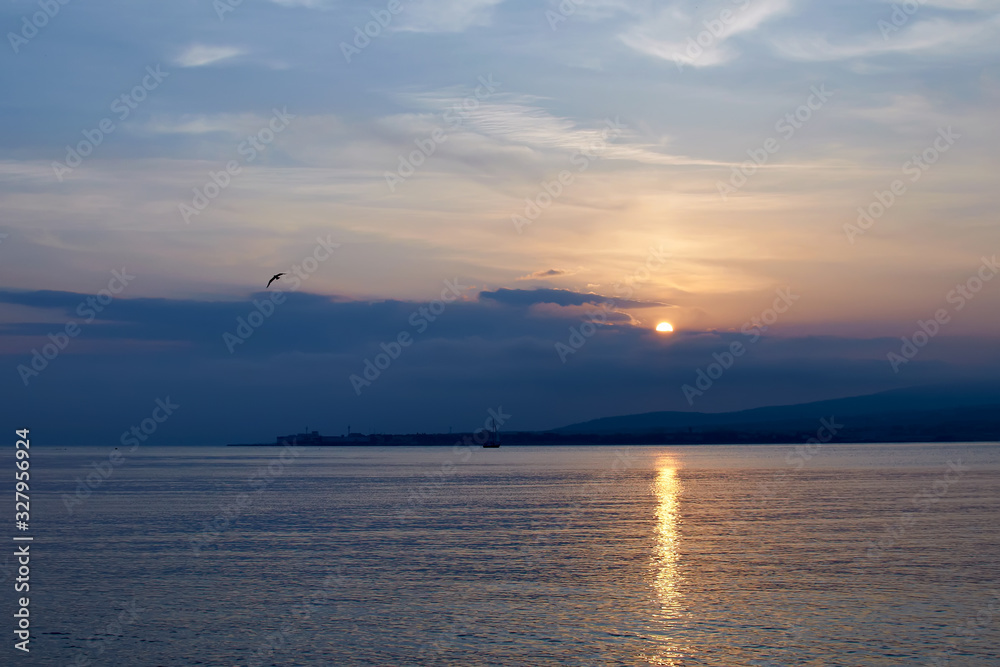 A beautiful sunset at sea in orange tones with seagulls and a sea vessel. Russia's Black Sea coast