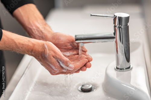 Washing hands man rinsing soap with running water at sink, Coronavirus prevention hand hygiene. Corona Virus pandemic protection by cleaning hands frequently.