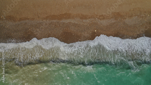 Aerial drone top view photo of emerald waves reaching sandy open ocean shore
