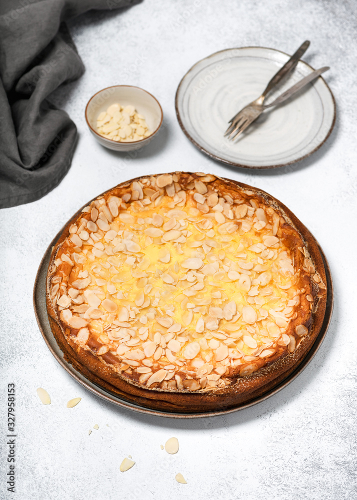 Traditional Cheese cake sprinkled with almonds flakes on a light rustic background. Delicious homemade sweet food concept. Selective focus.