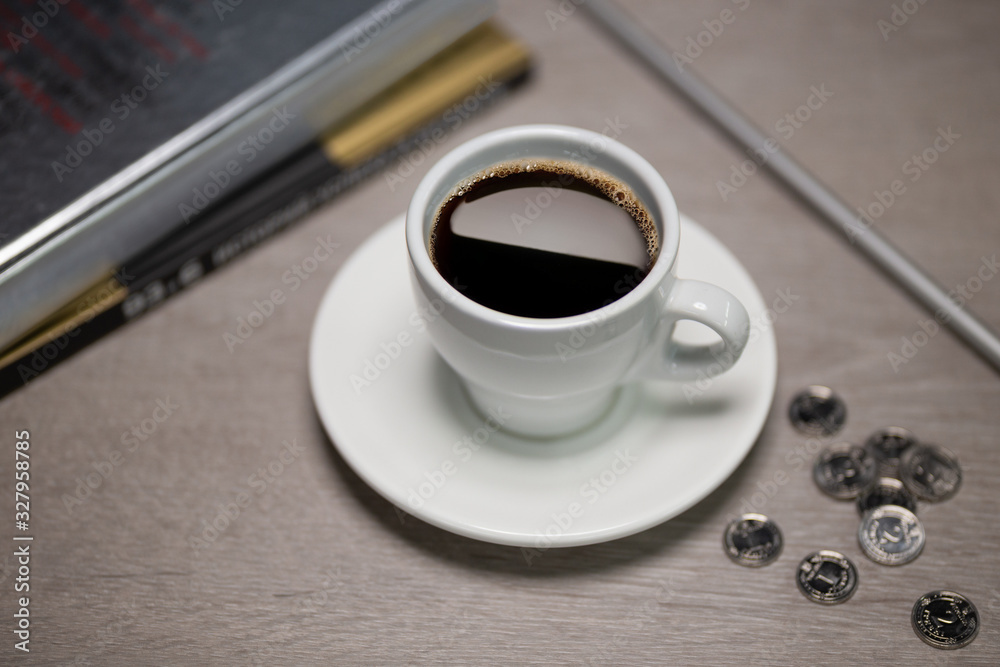 Cup of coffee on a table with books and silver coins Cup of coffee on a table with books and silver coins