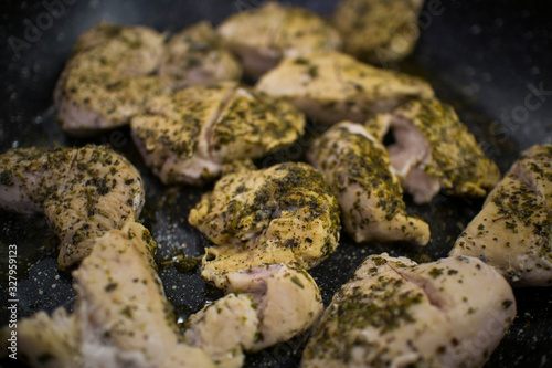 cooking chicken chopped in slices with herbs in a dark pan top view
