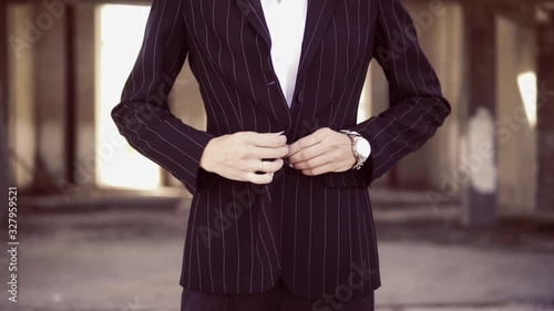 unrecognizable woman in pantsuit fastens a button on a jacket
