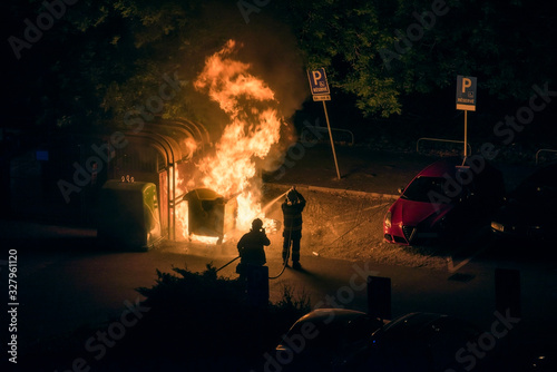 Firefighters Extinguish Burning Plastic Dumpster near Parking Lot at Night