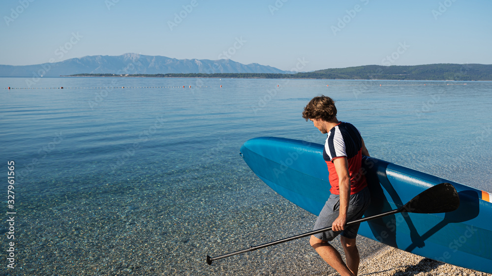 Young man carrying sup board