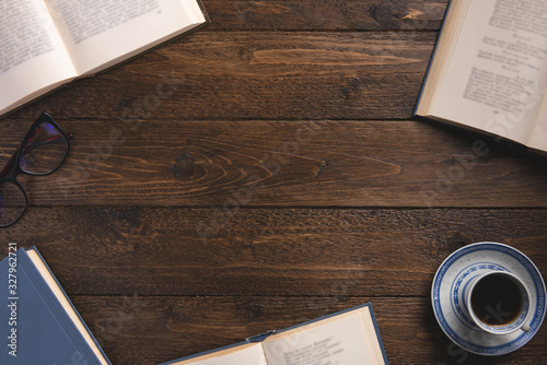 Cozy morning concept. Open books, cup of coffee, glasses, on wooden background. Flat lay, top view, copy space.