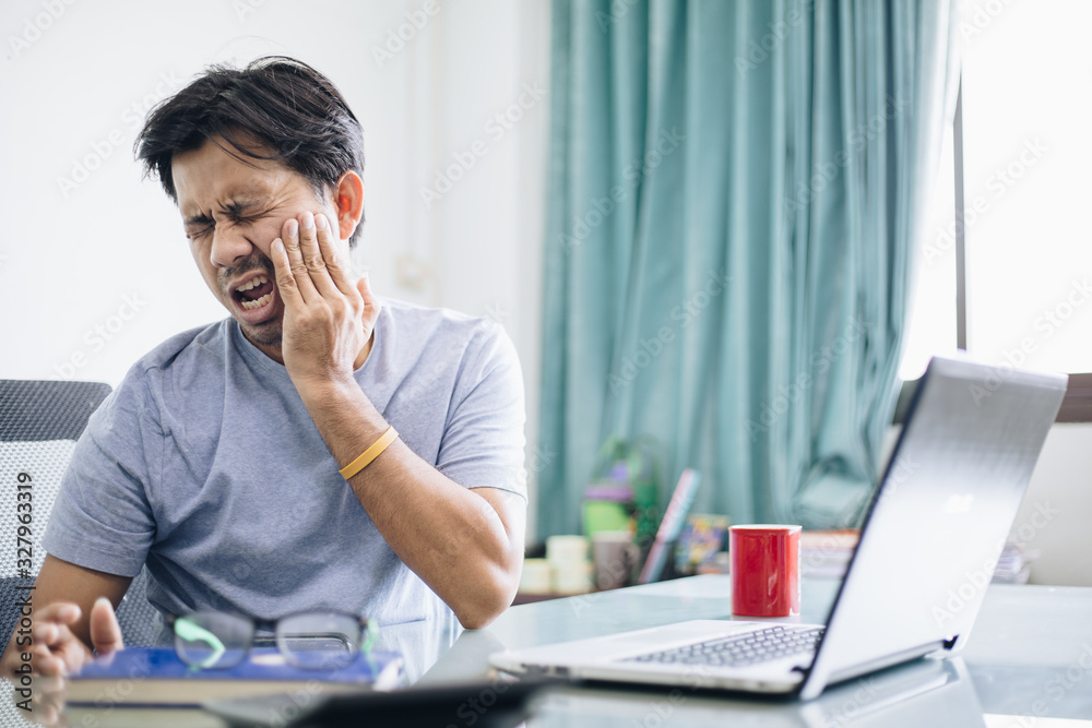 Freelance Asian man is having a toothache in office Freelance Asian man is having a toothache in office