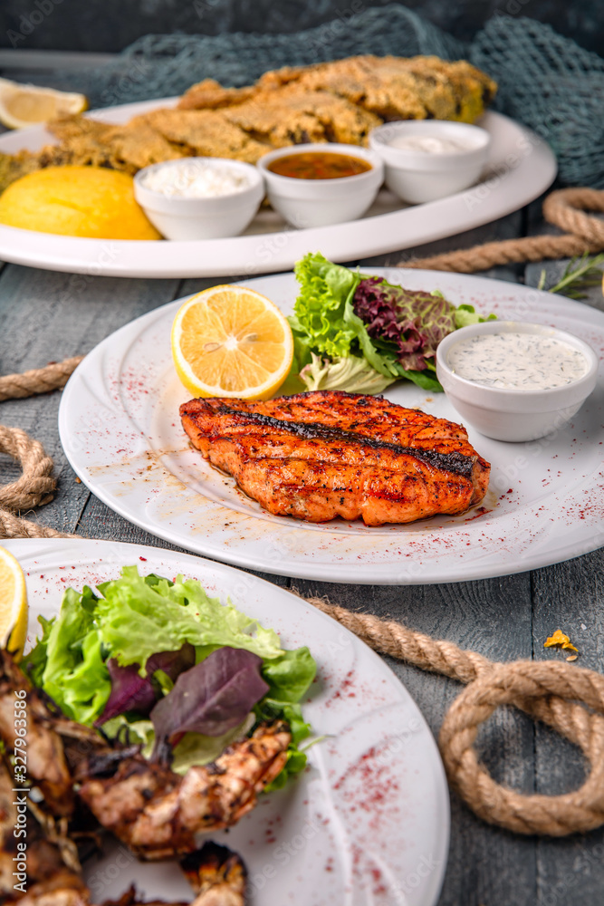 Festive table, delicious food for meeting friends. A variety of fish and meat dishes: salmon, shrimp, steak and salads. Festive table, delicious food for meeting friends. A variety of fish and meat dishes: salmon, shrimp, steak and salads.
