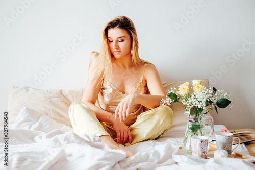 Blonde woman in pajamas having breakfast in bed photo