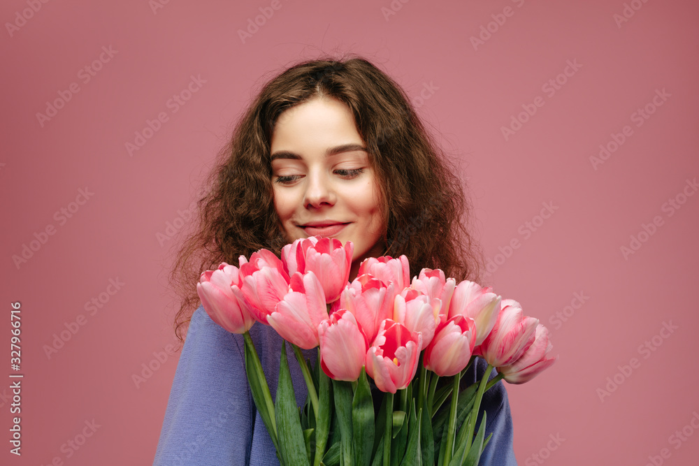Young beautiful girl holding bouquet of pink tulips flowers