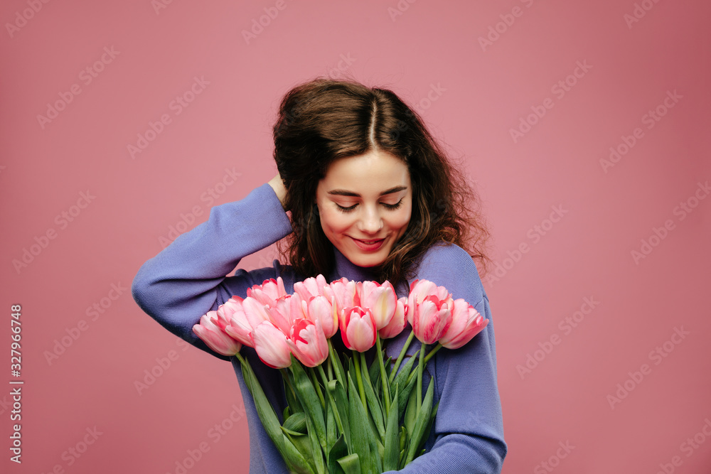 Girl holding bouquet of spring flower tulips against pink background. International womans day Girl holding bouquet of spring flower tulips against pink background. International womans day