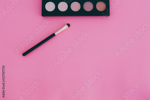 cosmetics products still-life, eyeshadow palette with brush on minimaist pink background and copyspace