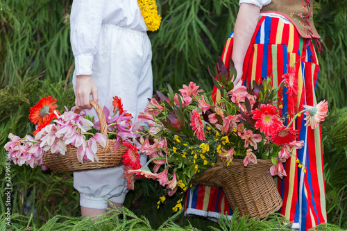 Young teen male and female wearing traditional clothe of Madeira island folklore holding a flower basket at "Madeira Flower Festival" in Madeira island, Portugal