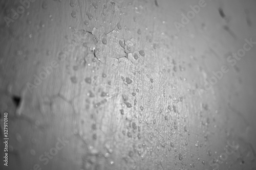 White wall with cracks and drops of water, close-up at an angle.