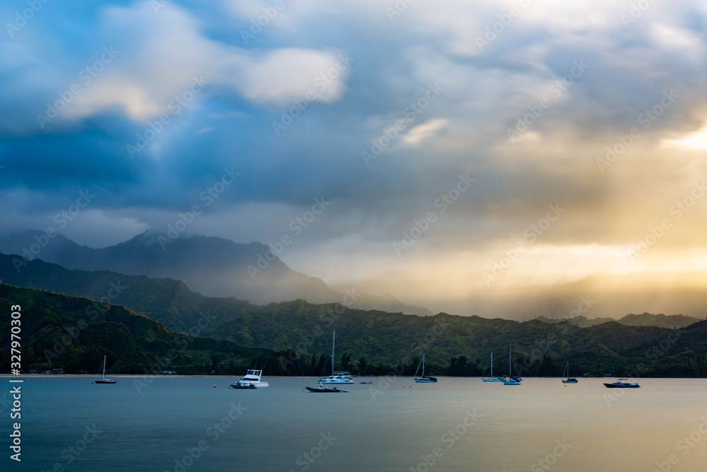 sailboats at Hanalie Bay beach, Kauai, Hawaii at sunset with mountains in the background